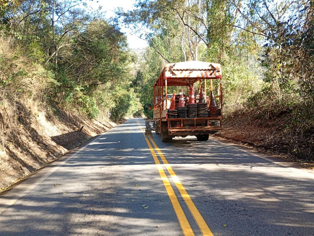 Caminhão de sinalização em trecho de rodovia cercado por mata
